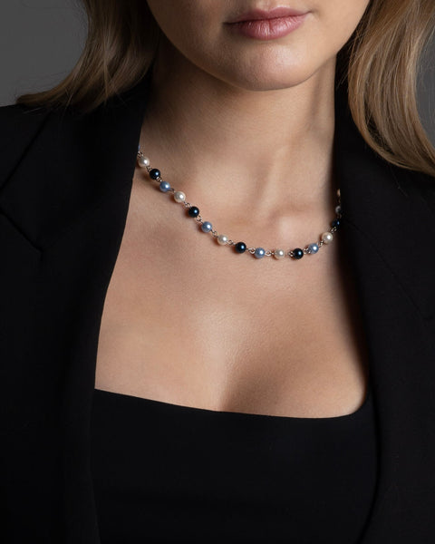 A women wearing the FIVE JWLRY pearls necklace made with 2 shades of blue glass beads and white pearls, crafted with natural shell. 45cm + 5cm extension, rollo chain for adjustment. Fashion accessory, statement jewelry. Designed in Montreal, Canada.