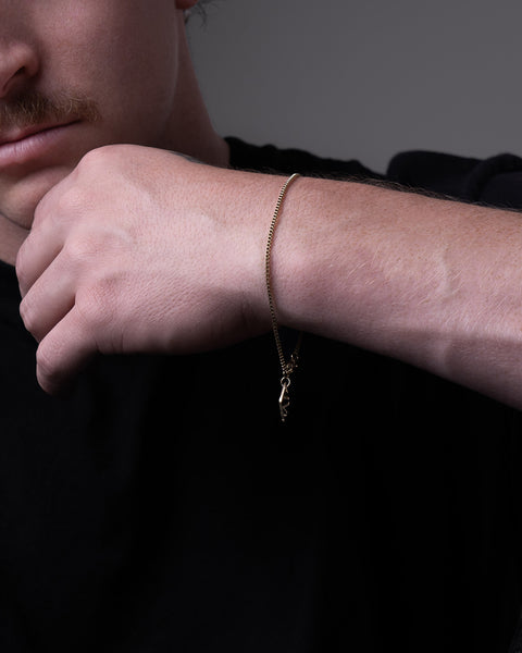 Clyd bracelet by Five Jwlry for men, designed in Montreal. Features a 1.5mm square box chain in 14k gold color, highlighted with the brand's signature logo tag