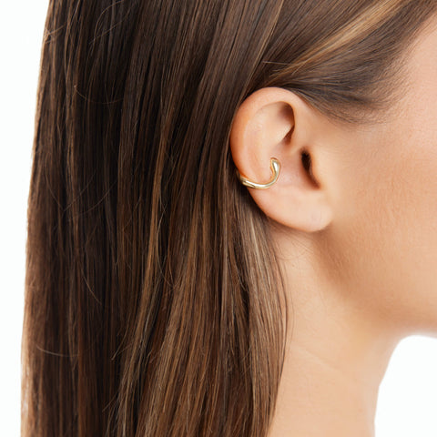 "Dusk women's ear cuff by Five Jwlry, part of Alicia Moffet's collaboration. This organically shaped piece elegantly wraps around the ear, requiring no piercing. Available in 14k gold or silver, crafted from water-resistant 316L stainless steel. Hypoallergenic with a 2-year warranty.
